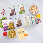Flatlay der 4-Tage-Foodkur mit zusätzlichem Proteinmix von LiveFresh: drei Porridge-Sorten, Proteinshake in Dose, veganes Tikka Masala, eine frische Bowl, zwei kaltgepresste Säfte, Nahrungsergänzung und der offizielle Foodkur-Guide. Frische Zutaten wie Orange, Beeren und Salat ergänzen die Szene.