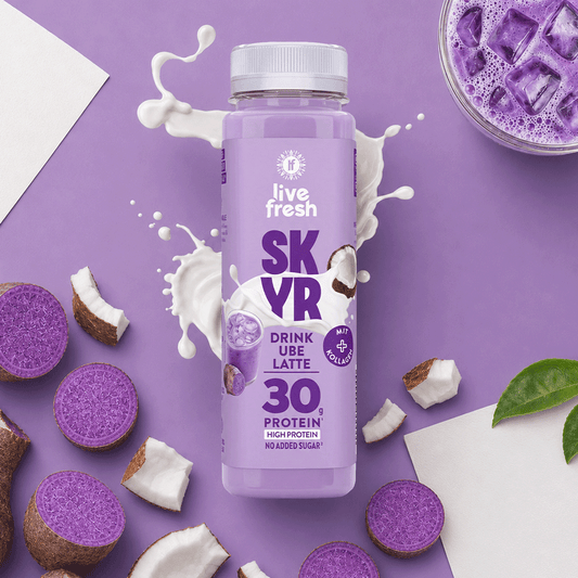 Ube Latte Skyr Drink von LiveFresh auf lila Hintergrund mit 30g Protein Label. Daneben Kokostückchen und offene Ube Knollen. Außerdem Milch und ein Glas Ube Latte mit Eiswürfel.