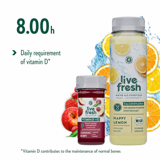 Two LiveFresh drinks, a Vitamin D3 + K2 Shot “Sunshine Berry” with berries and apple, and a large bottle of low-calorie infused water “Happy Lemon” with lemon and orange, placed in front of fresh fruit and  water splash, with a reference to covering the daily vitamin D requirement.