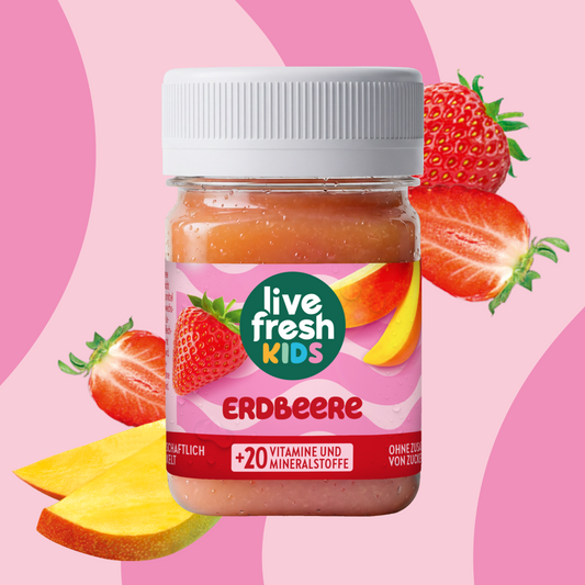 LiveFresh Kids Aardbei in een potje tegen een roze achtergrond met aardbeien en stukjes mango. Op het etiket staat "live fresh KIDS", "AARDBEI" en "+20 VITAMINEN EN MINERALEN".
