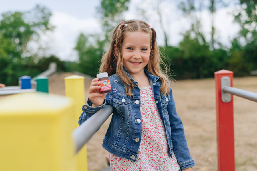 Een meisje op een speelplaats houdt een LiveFresh Kids Shot Aardbei in haar hand.