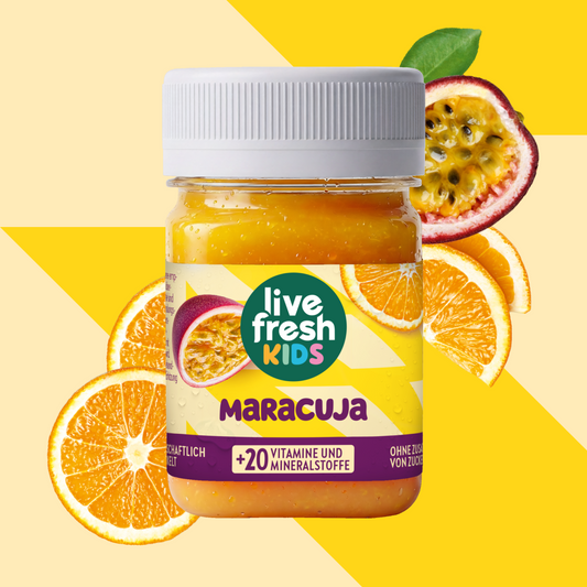 LiveFresh Kids Maracuja in een glas tegen een gele achtergrond met passievrucht en sinaasappelschijfjes. Op het etiket staat "live fresh KIDS", "MARACUJA" en "+20 VITAMINEN EN MINERALEN".