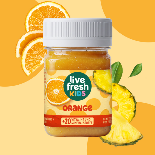 LiveFresh Kids Orange in een glas tegen een oranje achtergrond met verse sinaasappelschijfjes en stukjes ananas. Op het etiket staat "live fresh KIDS", "ORANGE" en "+20 VITAMINEN EN MINERALEN".