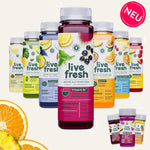Mehrere LiveFresh Säfte und Shots in verschiedenen Farben in einer Gruppenanordnung. Im Vordergrund steht die Sorte Kombucha Ritual in dunklem Rot, dahinter Sorten wie Happy Lemon, Grüne Gefühle, Keep Cool, Goldrausch, Sommer Gefühle und Glow Flow. Auf den Etiketten sind Zutaten wie Zitrone, Beeren, Orange und Spinat abgebildet. Oben rechts befindet sich ein ‘Neu’-Badge.