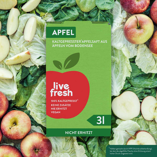 Eine „Live Fresh“ Verpackung für kaltgepressten Apfelsaft aus Äpfeln vom Bodensee. Die Verpackung hat ein auffälliges Apfel-Logo und trägt den Text „100% Kaltgepresst, Keine Zusätze, Nie Erhitzt, Vegan“. Der Karton enthält 3 Liter Apfelsaft und ist nicht erhitzt, wie auf der Verpackung hervorgehoben wird. Im Hintergrund sind frische Äpfel und grünes Blattgemüse zu sehen.