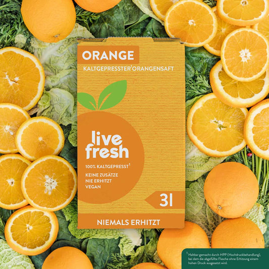 Eine „Live Fresh“ Verpackung für kaltgepressten Orangensaft mit 3 Litern Inhalt. Auf der Verpackung steht „100% Kaltgepresst, Keine Zusätze, Nie Erhitzt, Vegan“ und „Niemals Erhitzt“. Im Hintergrund sind frische Orangen und geschnittene Orangenscheiben auf grünem Blattgemüse zu sehen. Die Verpackung hebt die Qualität und Frische des Safts hervor, der durch das Hochdruckverfahren (HPP) haltbar gemacht wird, ohne erhitzt zu werden.