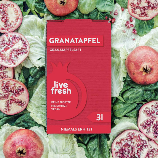 Eine „Live Fresh“ Verpackung für Granatapfelsaft mit 3 Litern Inhalt. Die rote Verpackung trägt den Text „Keine Zusätze, Nie Erhitzt, Vegan“ sowie „Niemals Erhitzt“. Der Hintergrund besteht aus geschnittenen Granatäpfeln und grünem Blattgemüse, was die Frische und Natürlichkeit des Produkts unterstreicht. Die Verpackung hebt die kaltgepresste, unverarbeitete Qualität des Safts hervor