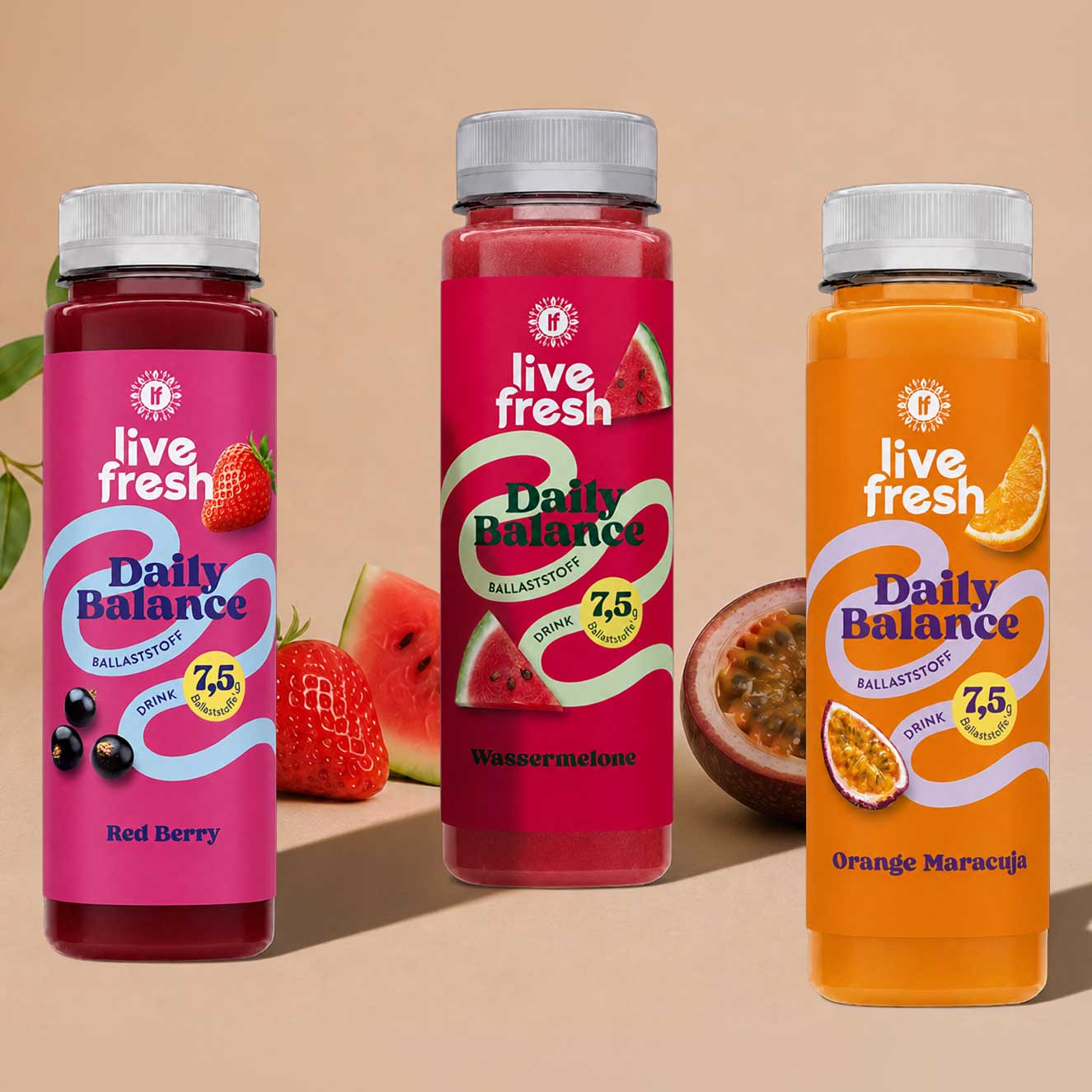 Drei Flaschen des Daily-Balance Probierpakets von Live Fresh stehen vor einem beigen Hintergrund, umgeben von frischen Früchten passend zu den Sorten Red Berry, Wassermelone und Orange Maracuja. Auf den Etiketten steht „live fresh“, „Daily Balance“, „Ballaststoff Drink“, „7,5 g Ballaststoffe“ sowie die jeweiligen Sortennamen „Red Berry“, „Wassermelone“ und „Orange Maracuja“.