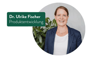 Zeigt Dr. Ulrike Fischer, die lächelnd in die Kamera blickt. Sie trägt eine dunkelblaue Jacke und ein weißes Oberteil. Links von ihr steht ihr Name und Titel in einem grünen Rechteck: „Dr. Ulrike Fischer, Produktentwicklung“. Im Hintergrund sind unscharfe grüne Pflanzen zu sehen, was eine frische und natürliche Atmosphäre schafft.