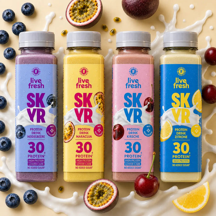Vier „live fresh SKYR“ Protein Drinks in den Sorten Heidelbeere, Maracuja, Kirsche und Zitrone stehen nebeneinander vor einem cremefarbenen Hintergrund mit Milchspritzern und passenden Früchten. Auf den Flaschen steht „30 g Protein“, „High Protein“, „Lower Carb“ und „No Added Sugar“ sowie „mit Kollagen“.