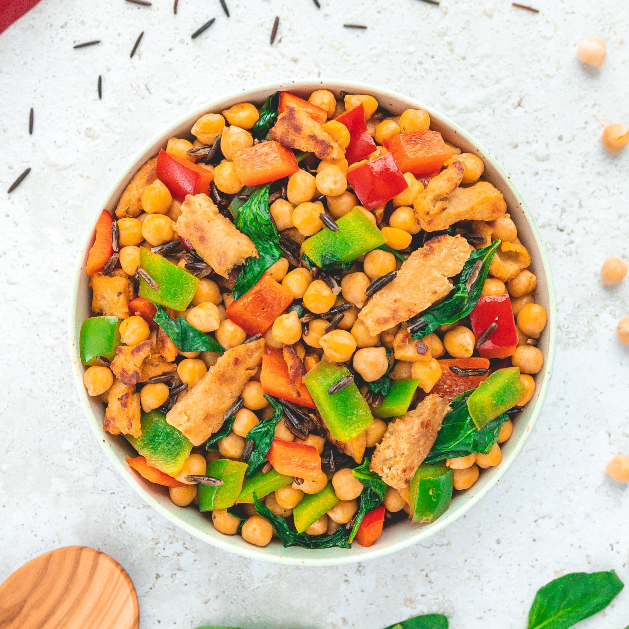 Eine bunte Schüssel mit einem Tikka Masala Gericht von LiveFresh. Es besteht aus Kichererbsen, roten und grünen Paprikastücken, Spinatblättern, Wildreis und pflanzlichem Fleischersatz. Die verschiedenen Zutaten verleihen dem Gericht ein ansprechendes, farbenfrohes Aussehen und betonen die ausgewogene Mischung aus Protein und Gemüse.