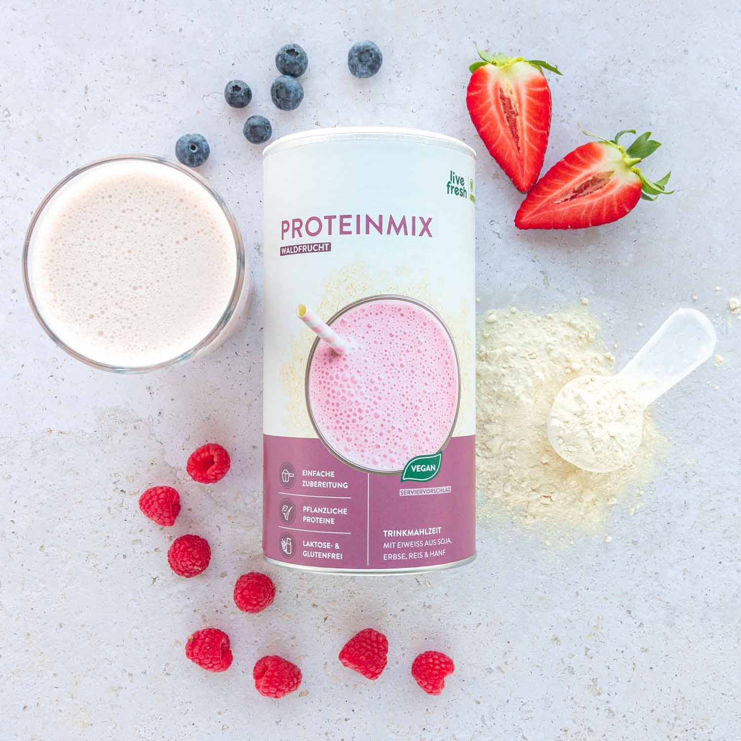 eganes Proteinpulver Geschmack Waldfrucht mit frisch zubereitetem Shake, umgeben von Himbeeren und Blaubeeren, symbolisiert eine fruchtige Proteinquelle.