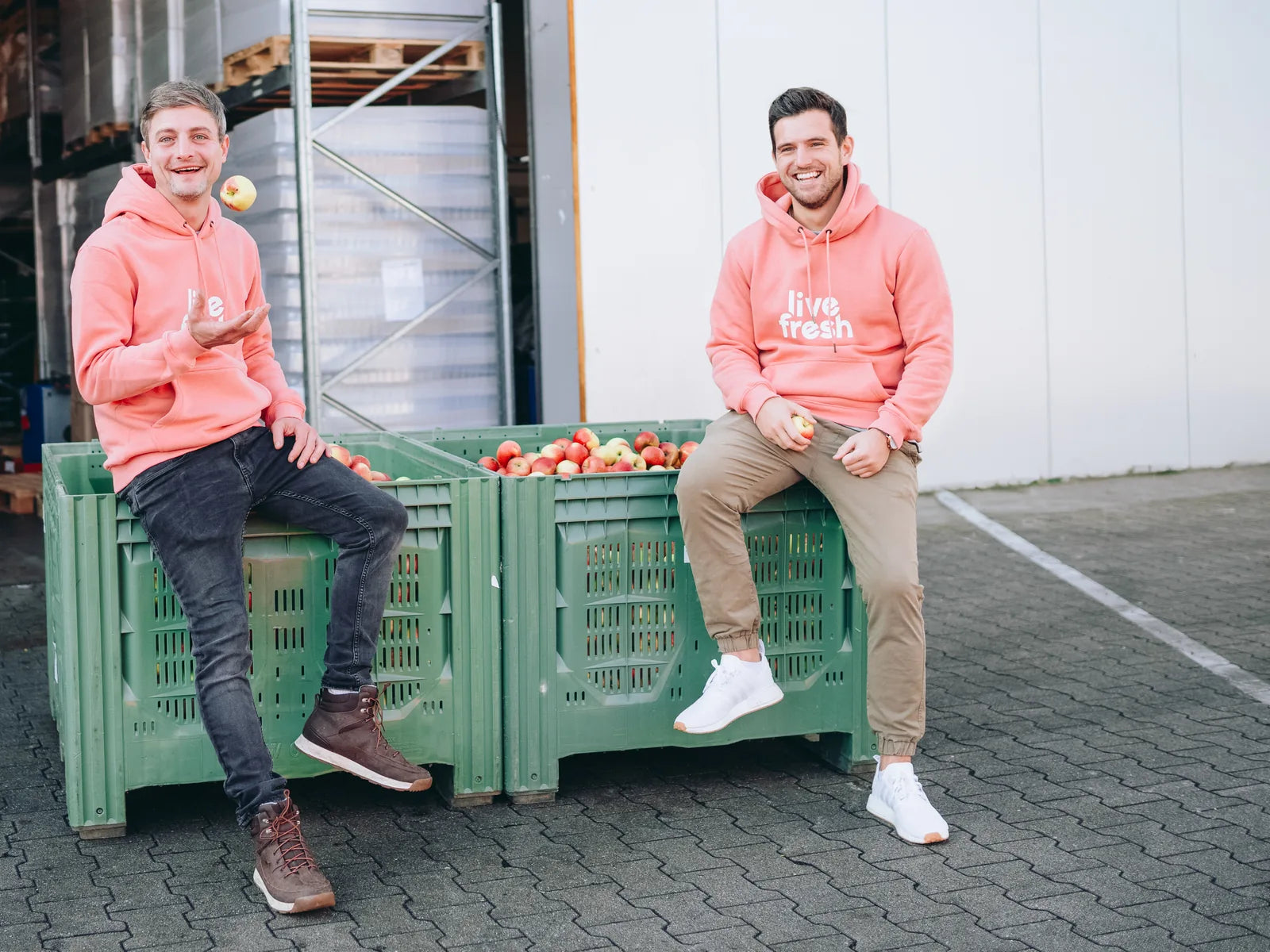 Simon und Bene, die Gründer von LiveFresh, auf Obstkisten vor der Produktion